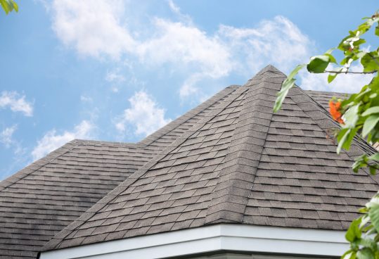 edge of Roof shingles on top of the house, dark asphalt tiles on the roof background.